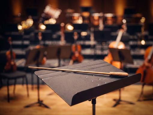 Conductor's baton in front of orchestra instruments.